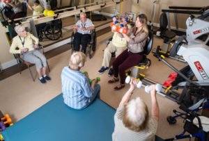 Caregiver with a group of seniors lifting weights
