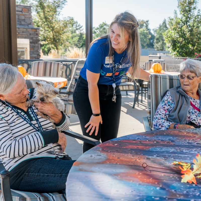 care partner talking to residents sitting on perogla square