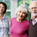 older couple and adult daughter smiling