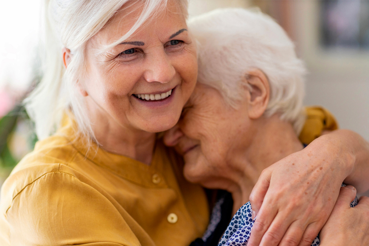 older woman and adult daughter hugging and smiling